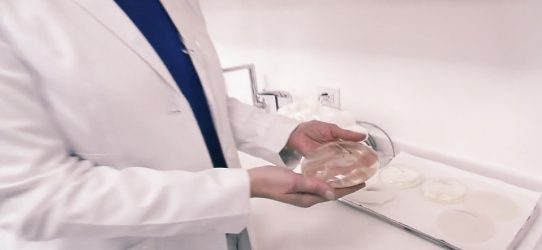Doctor holding breast implant and discussing breast implant illness